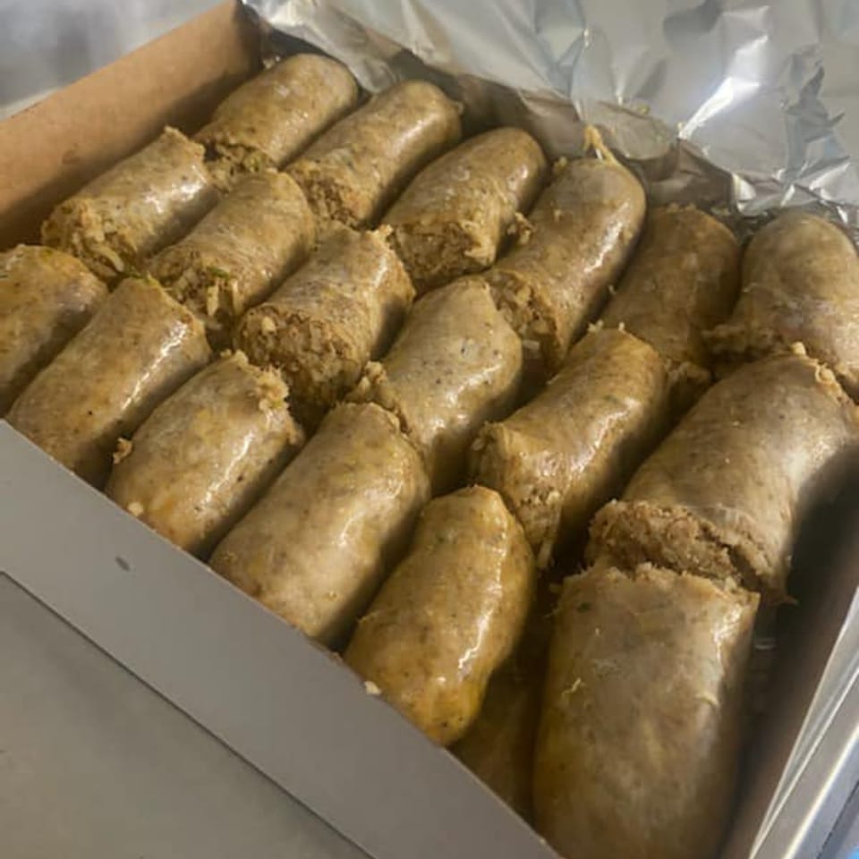 A box filled with rows of freshly made DezMeaux's Boudin, a Cajun sausage.