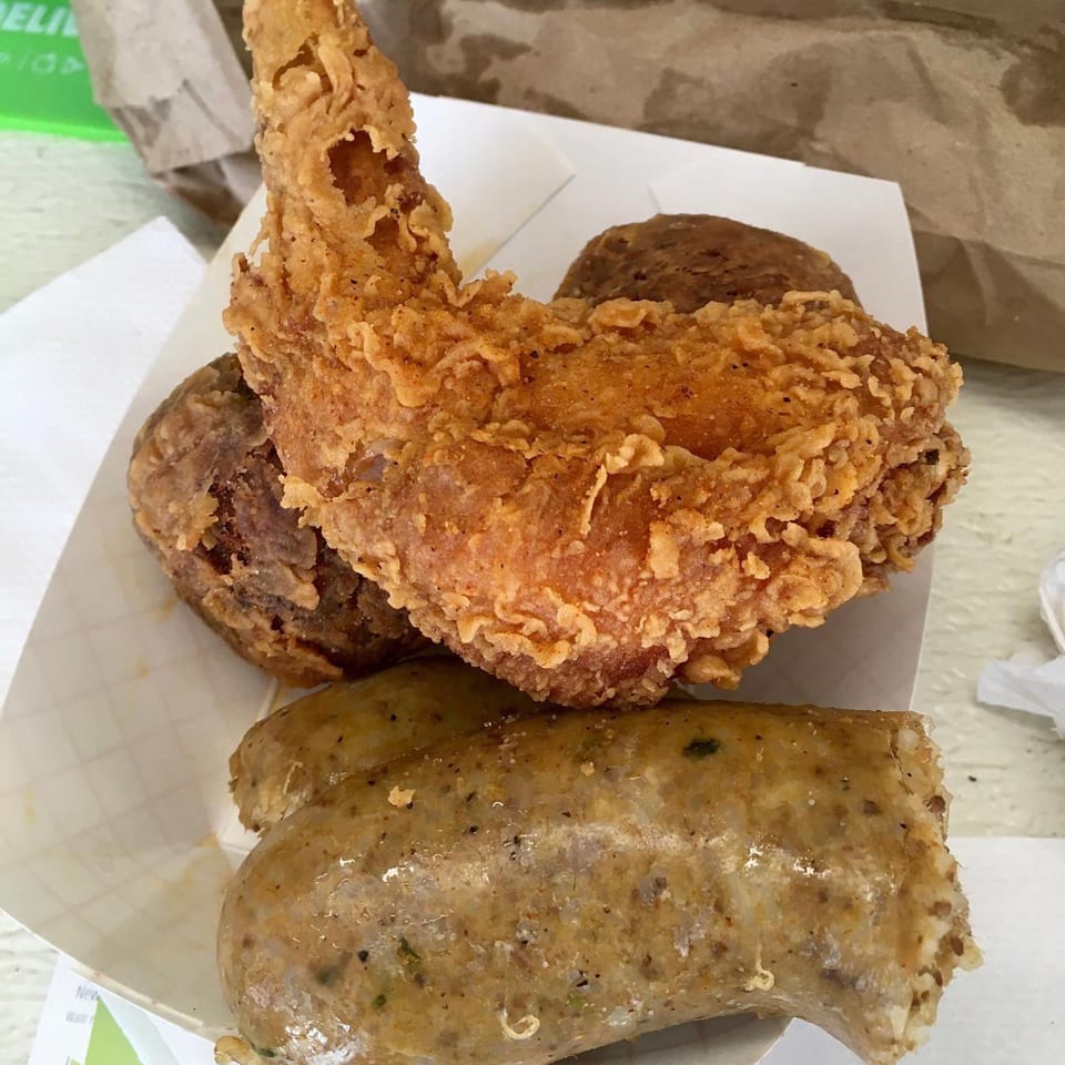 DezMeaux's Boudin fried chicken, boudin balls, and a large boudin sausage in a paper tray.